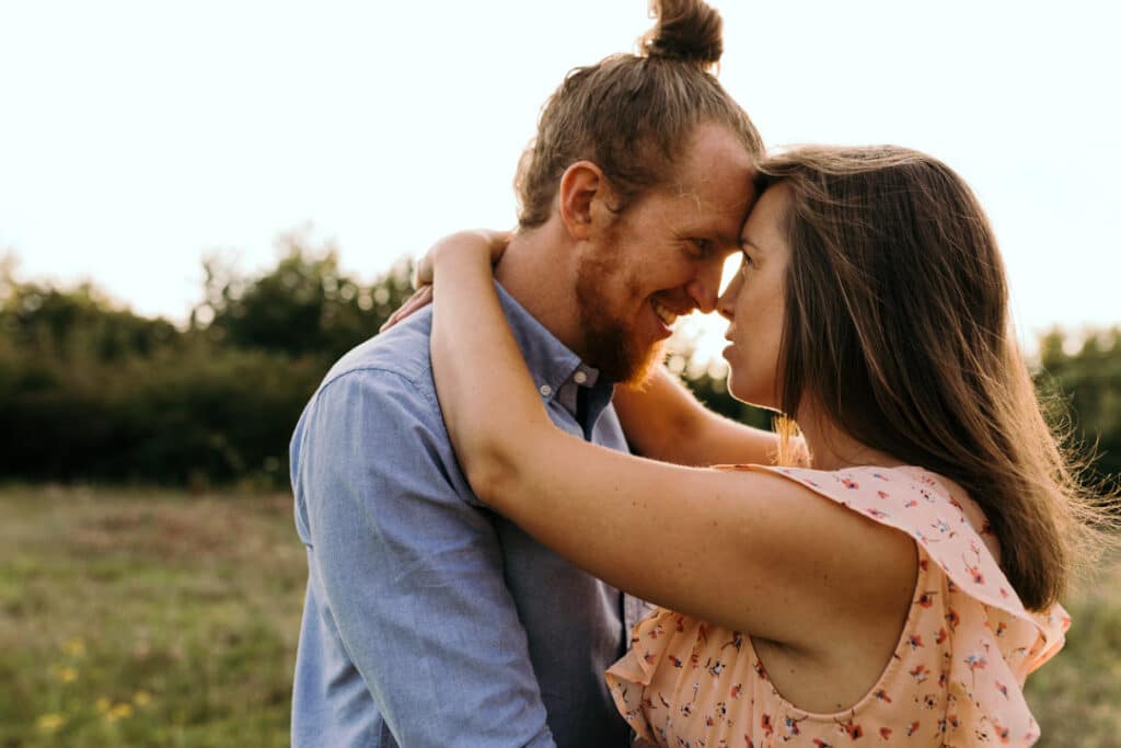 Woman and man are looking at each other. Sun is behind them. Lovely maternity photo session in Basingstoke. Ewa Jones Photography