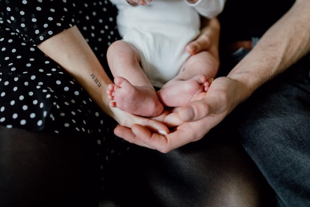 Detail shoot of newborn feet. Mum and dad are holding newborn feet and sitting on the sofa. Newborn photography in Hampshire. Ewa Jones Photography