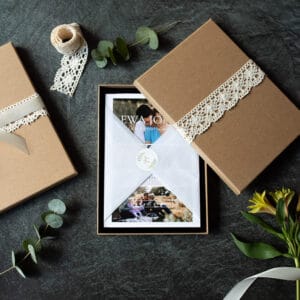 Photography gift vouchers. Gift voucher is in the middle lovely wrapped in tissue paper and inside brown box. on the side there are flowers and ribbons. Photography gift vouchers. Ewa Jones Photography