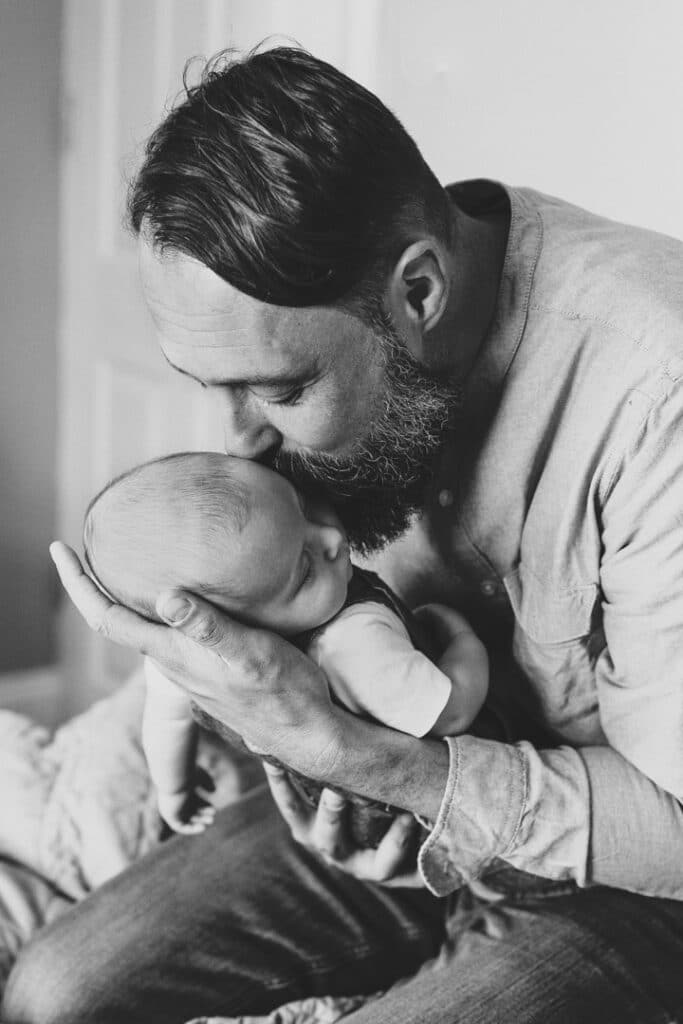 Dad is kissing his newborn baby during a newborn baby photo session. Reading, Berkshire. Ewa Jones Photography
