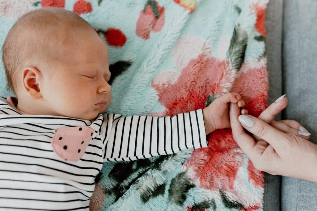 Mum is holding little newborn baby girl little fingers. Newborn baby girl is wearing a lovely top with black and white stripes. Newborn photographer in Basingstoke, Hampshire. Ewa Jones Photography