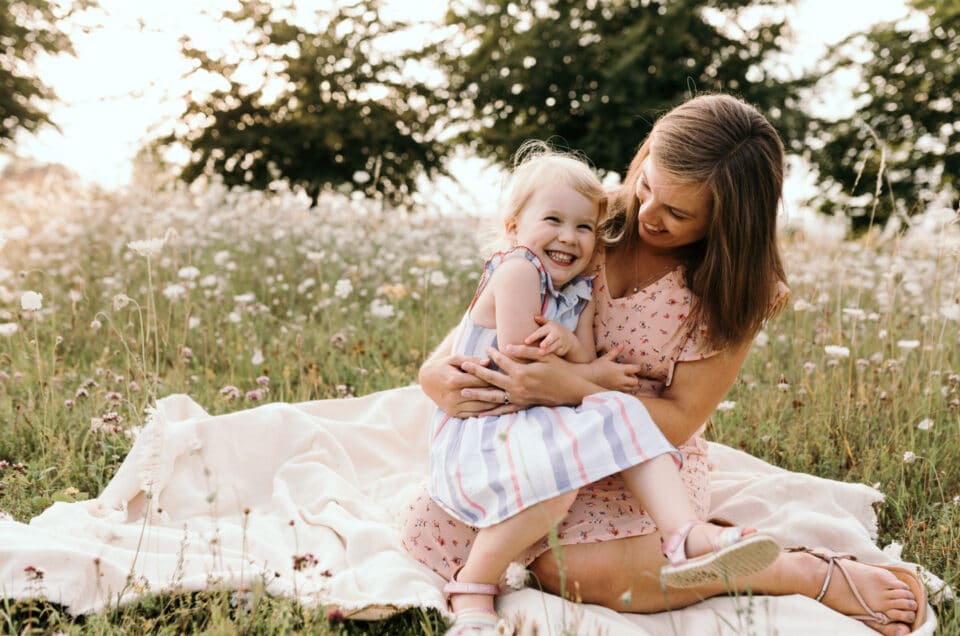 Pregnant mum is sitting on the blanket and cuddles her older daughter. When I met Jelly and learned how to do eyelash kisses. Hampshire maternity photography. Ewa Jones Photography