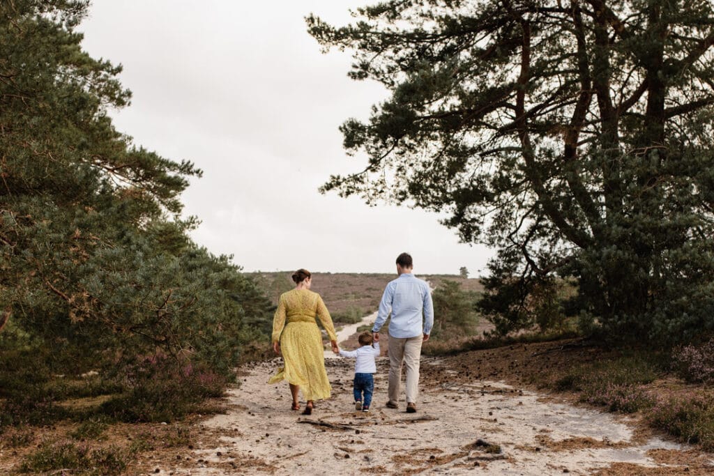 Mum, dad and their son are walking away in the lovely common in Fleet. Lovely golden hour family photo shoot in Hampshire. Family photography in Hampshire. Ewa Jones Photography