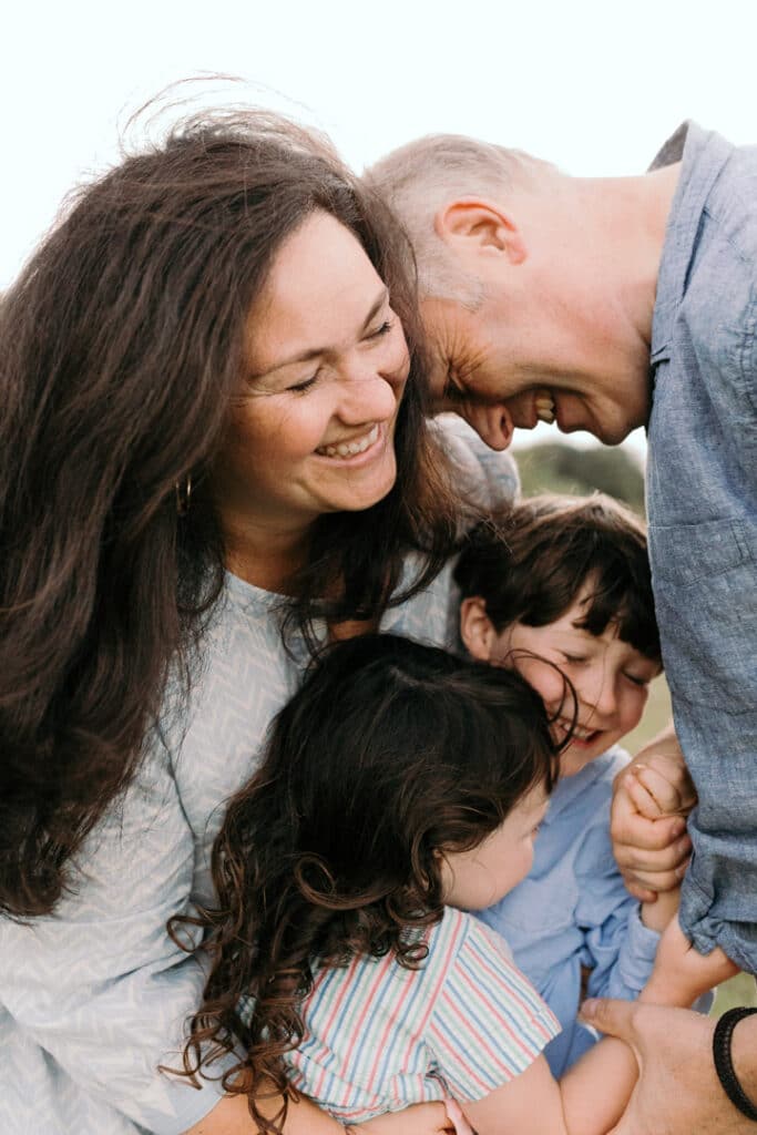 Family of four are cuddling tight to each other. They are all laughing. Lovely family moment. Family photography in Hampshire. Five tips on how to prepare for a family photo session. Ewa Jones Photography