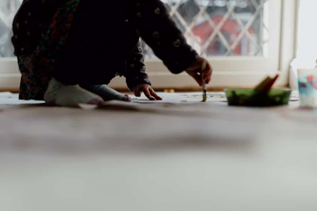 Close up detail of girl paining on the floor. Family photographer in Hampshire. Ewa Jones Photography