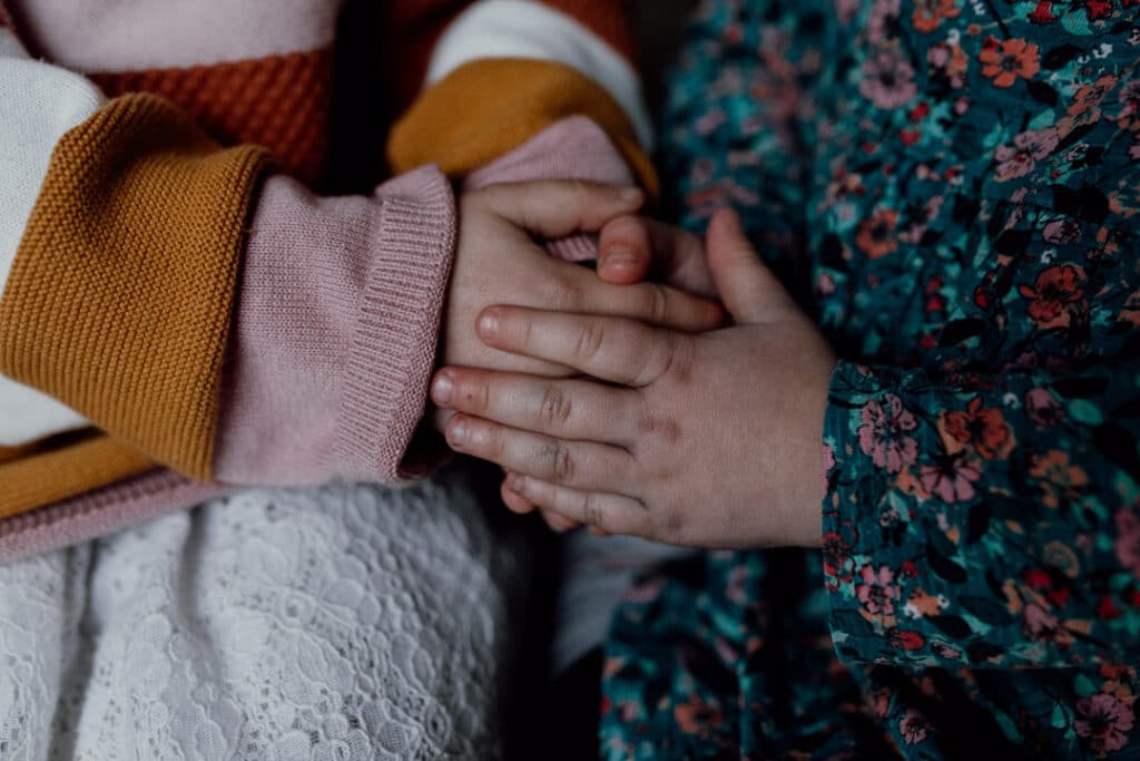 Two little sisters are holding hands together. Lovely candid photography moment. Family photographer in Hampshire. Ewa Jones Photography
