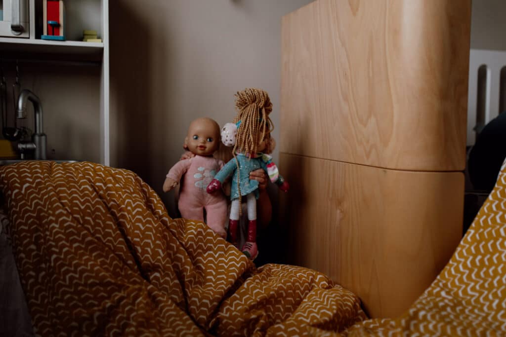 Playing the puppet show with dolls and made up curtain from the duvet. un-posed in home family photography in Hampshire. Ewa Jones Photography