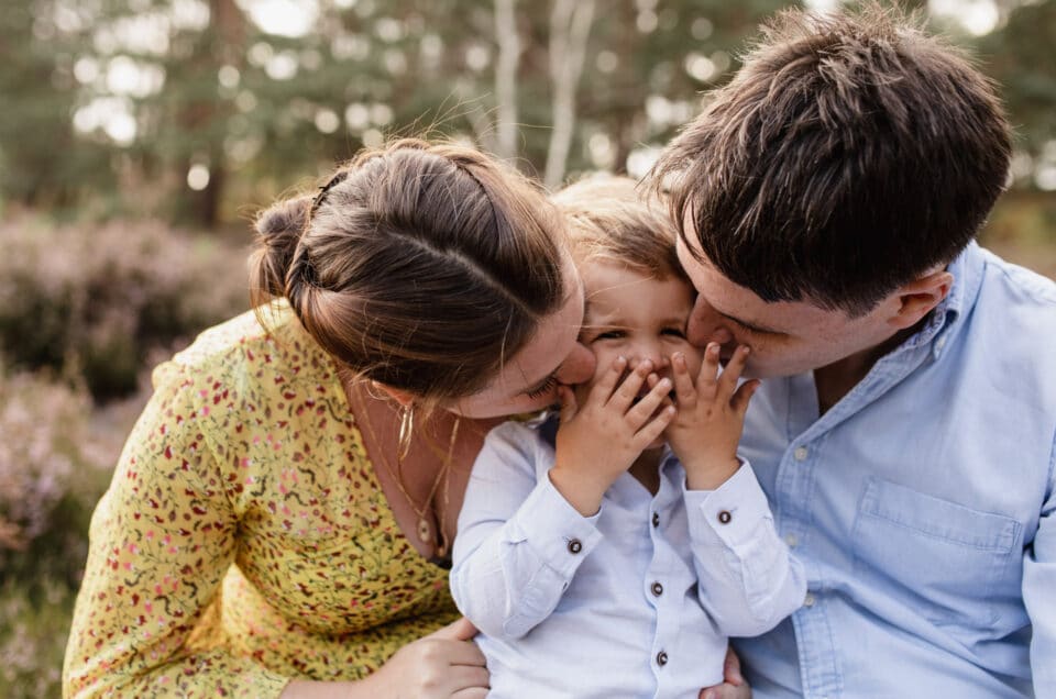 Mum and dad are kissing their boy in his cheeks. Natural lifestyle family photography. Family photoshoot in Basingstoke, Hampshire. Ewa Jones Photography