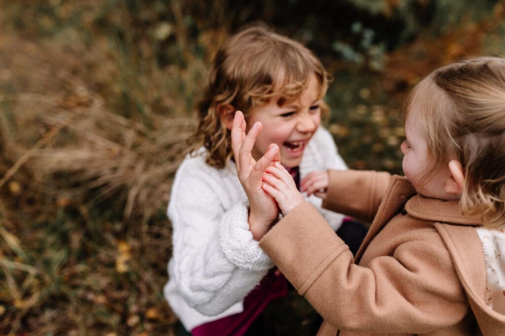 two cousins are looking at each other and smiling. Autumn family photo session in Hampshire. Ewa Jones Photography