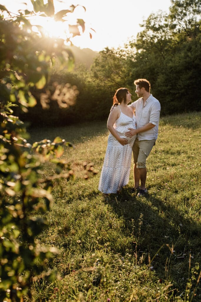 Mum and dad are standing next to each other and looking at each other and smiling. Lovely maternity photo session during golden hour. Maternity photographer in Hampshire. Ewa Jones Photography