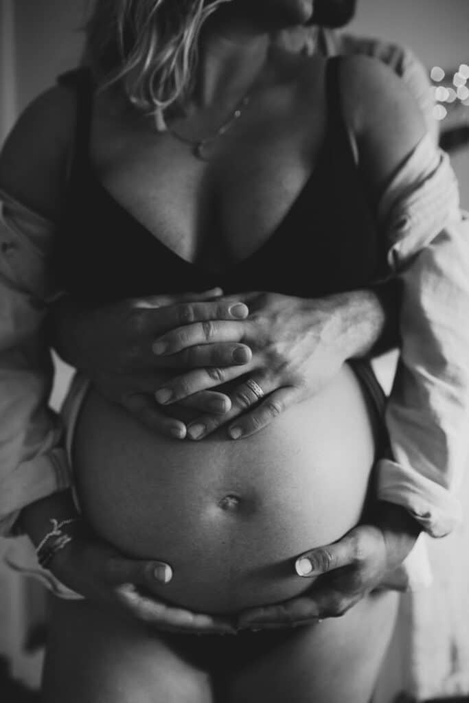 Pregnant mum is standing in baby nursery and her husband is hugging her and baby bump. Lovely in home maternity photography in hampshire. Ewa Jones Photography