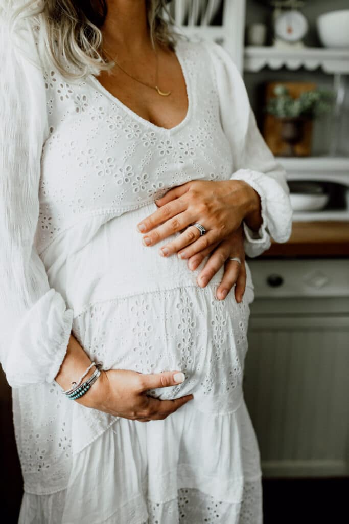 Pregnant mum is standing in the kitchen and has her hands on the bump. Maternity photographer in Hampshire. Ewa Jones Photography
