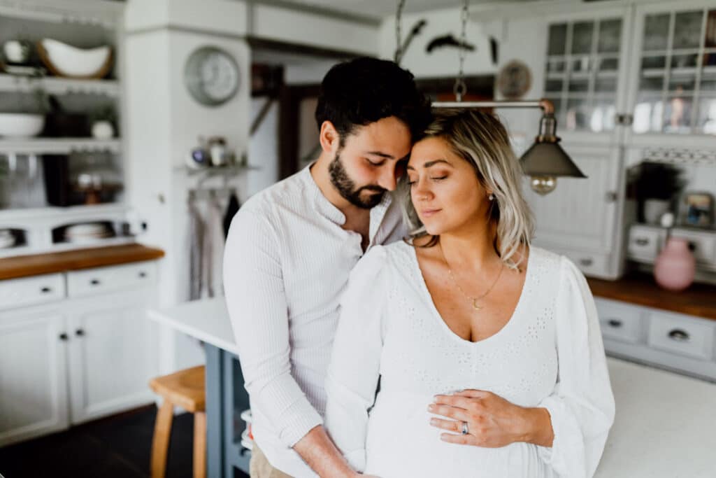 Expecting parents are cuddling up to each other. Lovely maternity photography in Hampshire. Ewa Jones Photography