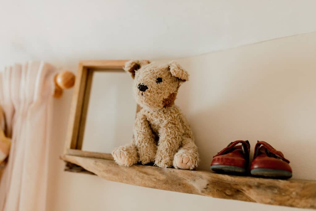 Baby nursery, rustic look. teddy bear and baby shoes on the shelf. Ewa Jones Photography