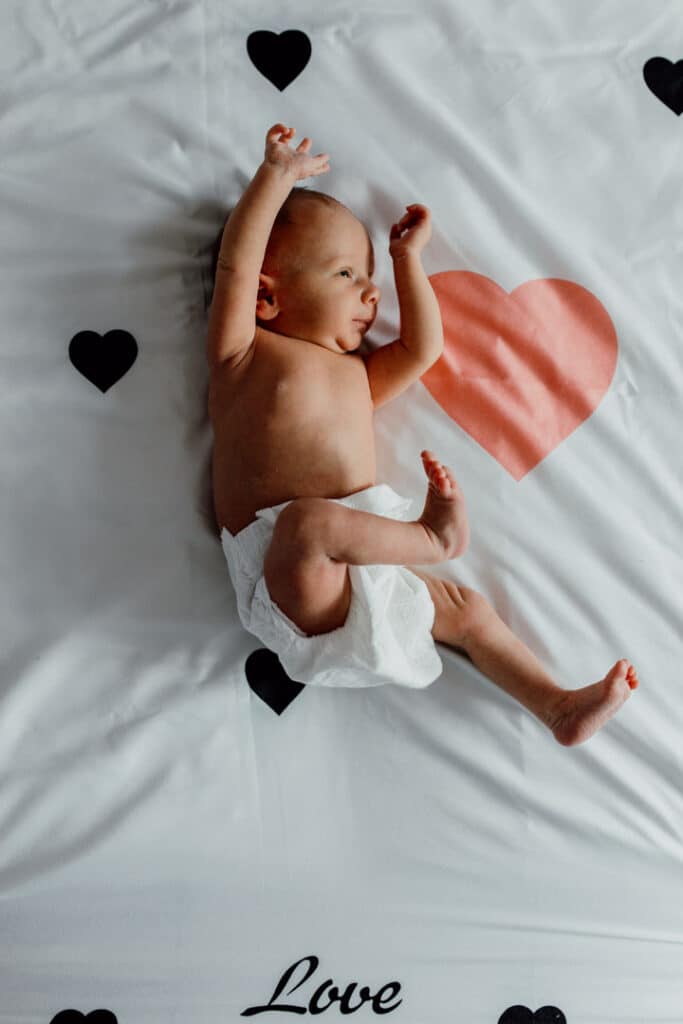 Newborn baby girl is stretching on the bed. Lovely candid newborn photography in Hampshire. Ewa Jones Photography