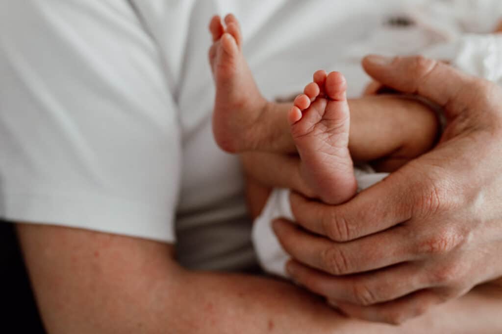 Close up feet details of the newborn baby feet. Dad is holding his baby girl in his hands. Newborn photographer in Hampshire. Ewa Jones Photography