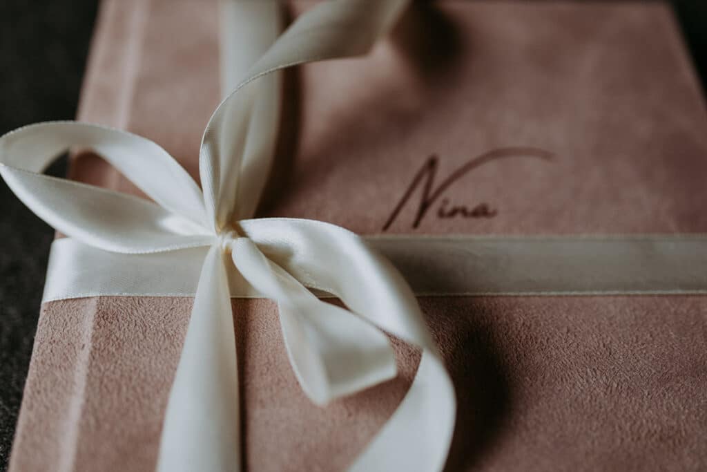 Close up detail of a newborn photo album. Pink cover with white ribbon. Newborn photography in Basingstoke. Ewa Jones Photography