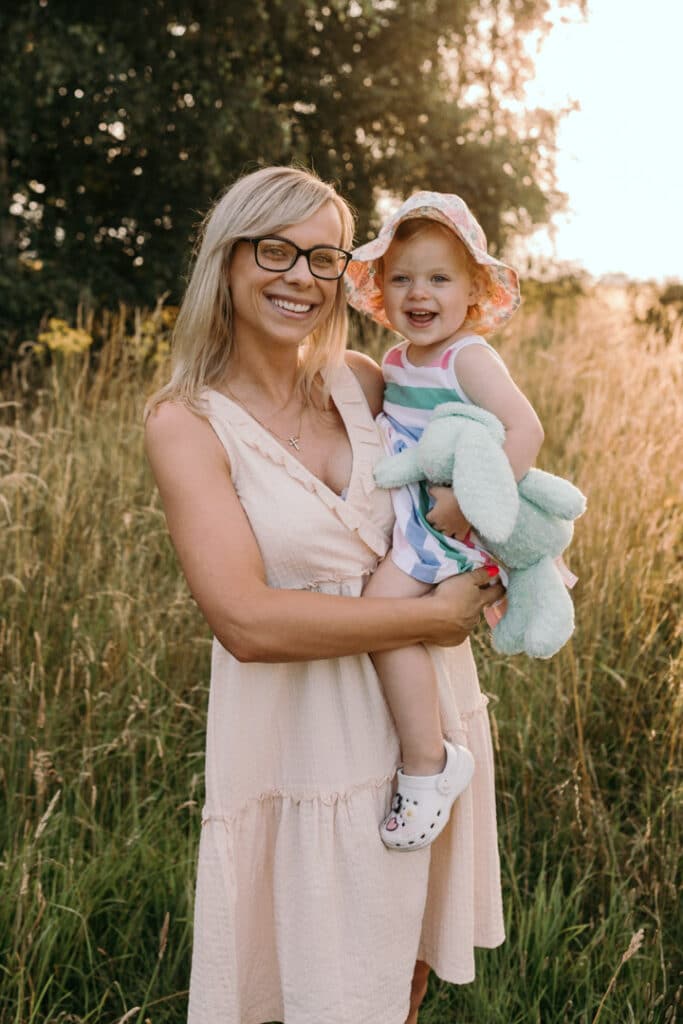 Mum and her girl are standing in the long grass. Mummy and me photo session in Hampshire. Ewa Jones Photography