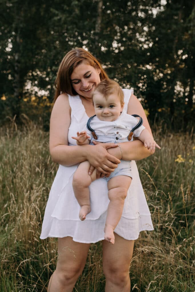 Mum is holding her little boy and looking down on him. Her boy is smiling at the camera. Family photo shoot. Family photographer in Hampshire. Ewa Jones Photography