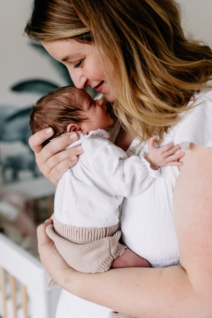 Mum is standing up and holding her newborn baby girl. she is smelling how lovely the newborn smell is. Newborn photographer in Basingstoke, Hampshire. Ewa Jones Photography