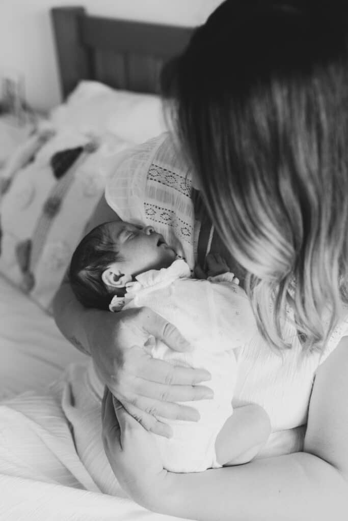 Mum is cuddling her baby girl and baby girl is sleeping. Newborn photographer in Hampshire. Ewa Jones Photography