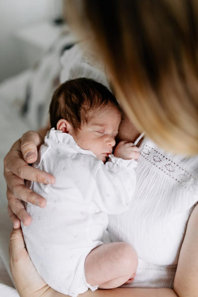 Mum is cuddling her baby girl and baby girl is sleeping. Newborn photographer in Hampshire. Ewa Jones Photography