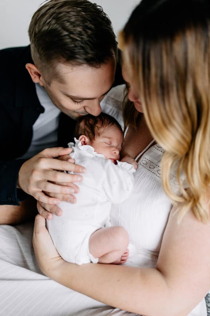 Mum and dad are hugging newborn baby girl which is sleeping. Newborn photography in Hampshire. Ewa Jones Photography