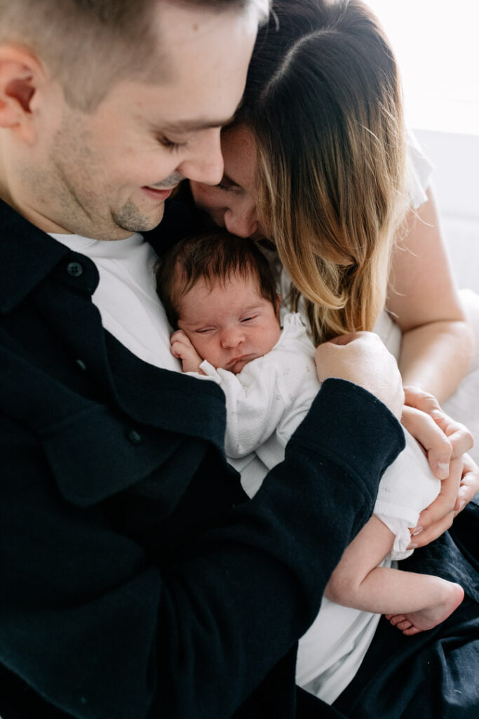 Mum and dad are cuddling up to their newborn baby girl. Newborn photographer in Hampshire. Ewa Jones Photography