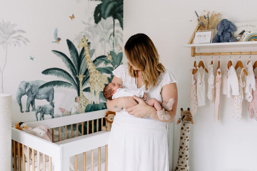 Mum is holding her newborn baby girl. Lovely natural light is coming through the windows. Newborn photographer in Hampshire. Ewa Jones Photography