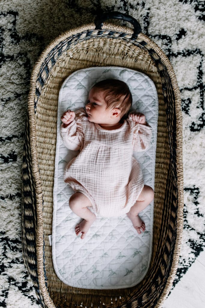 Newborn baby girl is laying inside her moses basket and looking up. In home newborn photography in Hampshire. Ewa Jones Photography