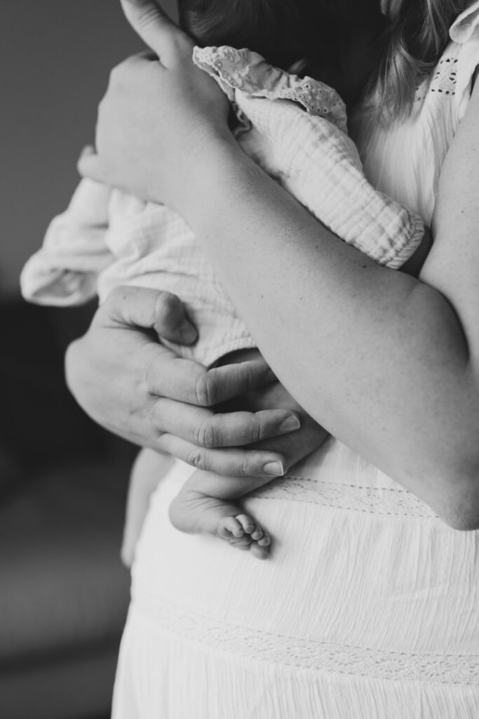 Mum is holding newborn baby girl in her arms. It's a black and white image. Newborn details. Newborn photo shoot in Basingstoke, Hampshire. Ewa Jones Photography