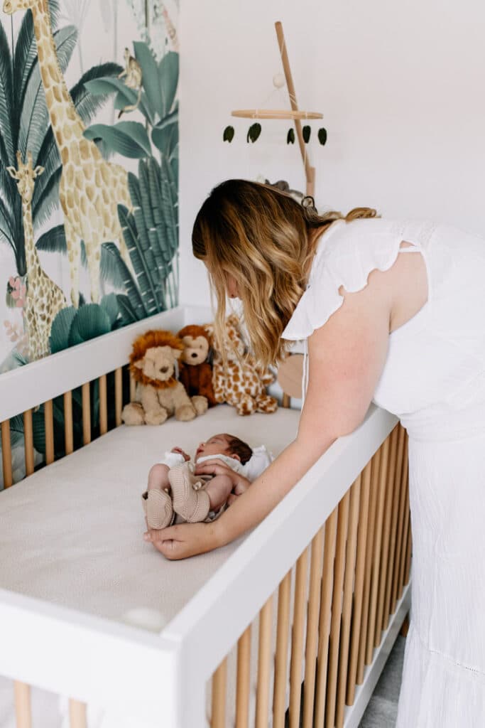 Newborn baby girl is laying in her cot in her beautiful jungle theme nursery. Newborn photo shoot in Hampshire. Ewa Jones Photography