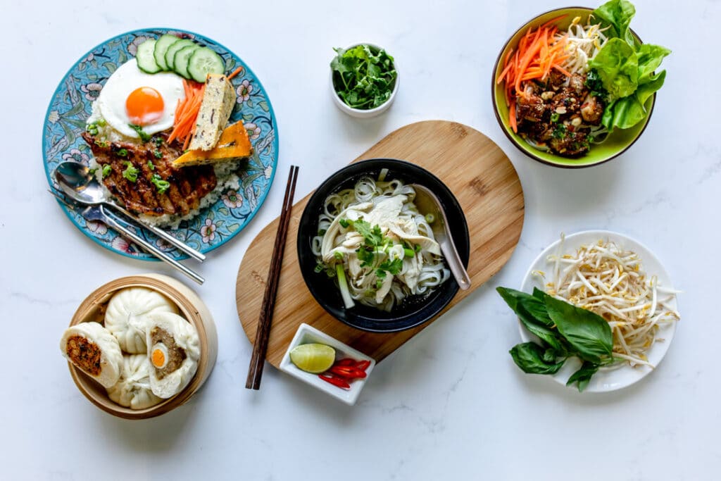 Various Vietnamese food on the marble table including chicken noodle soup, buns, stir fry. Food photography in Basingstoke, Hampshire. Ewa Jones Photography