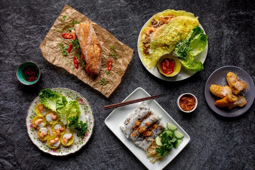 Variety of Vietnamese food including rice rolls, mini pancakes, fried bananas, chicken in bun. Food photography with Banana Blossom. Ewa Jones Photography