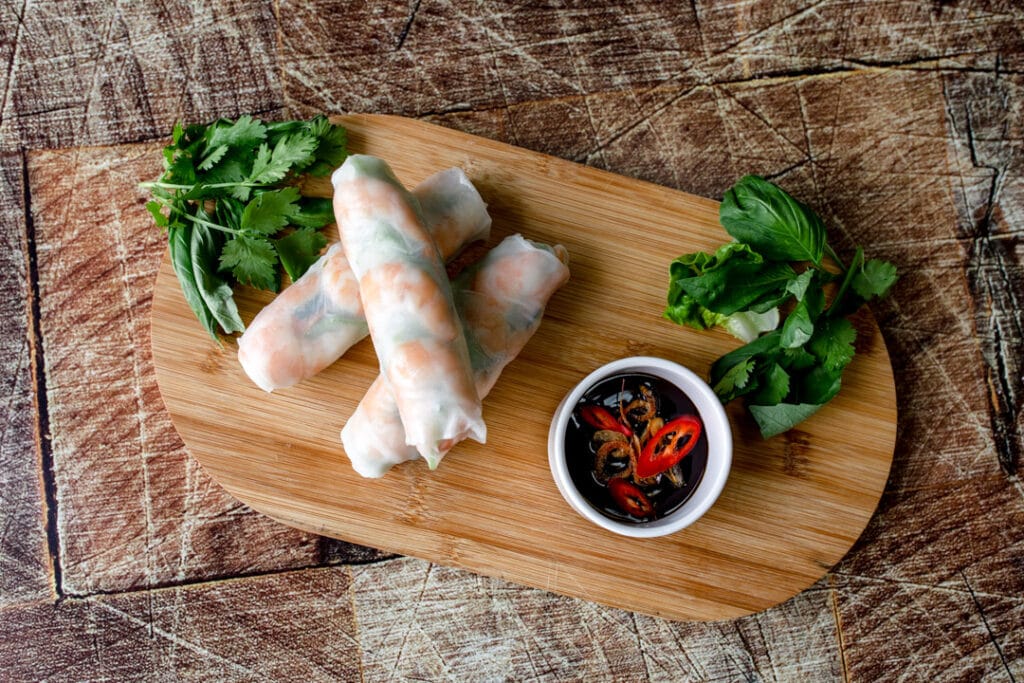 Vietnamese summer rolls on wooden chopping board with sauce. Food photography with Banana Blossom. Product photography in Hampshire. Ewa Jones Photography