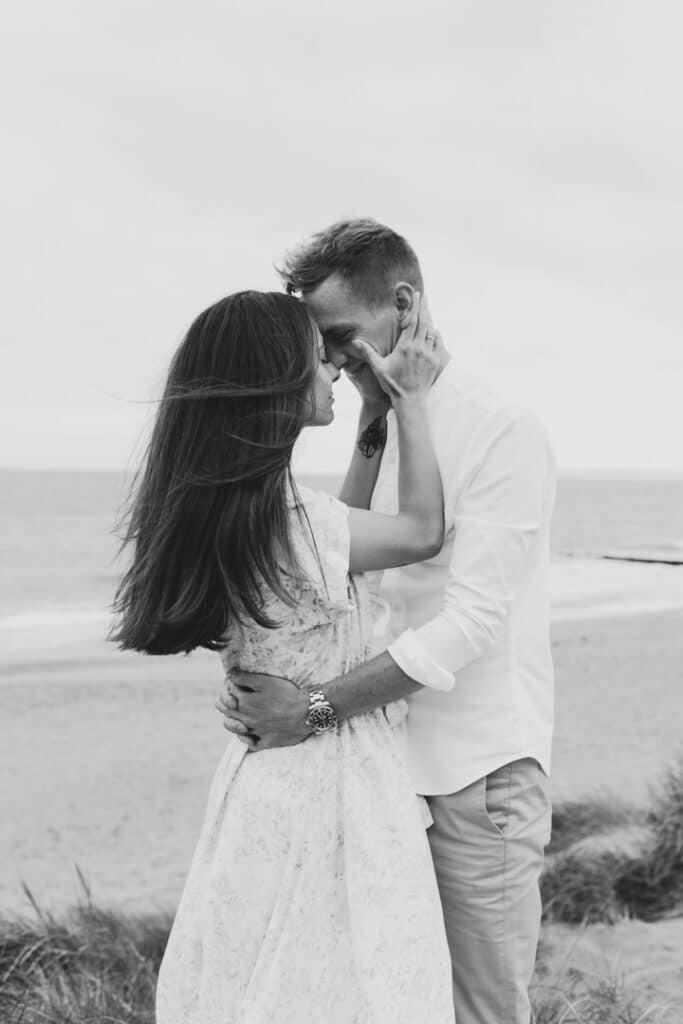 Couple is standing and holding close to each other. lovely romantic image of the couple at the beach. Couples Photographer in Hampshire. Ewa Jones Photography
