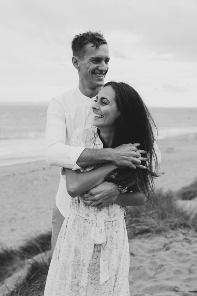 Couple is standing and holding close to each other. lovely romantic image of the couple at the beach. Couples Photographer in Hampshire. Ewa Jones Photography