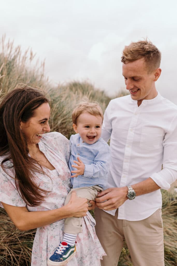 Mum is holding her son and looking at him. the little boy is smiling. Lovely natural family photo session at the beach. Family photographer in Hampshire. Ewa Jones Photography