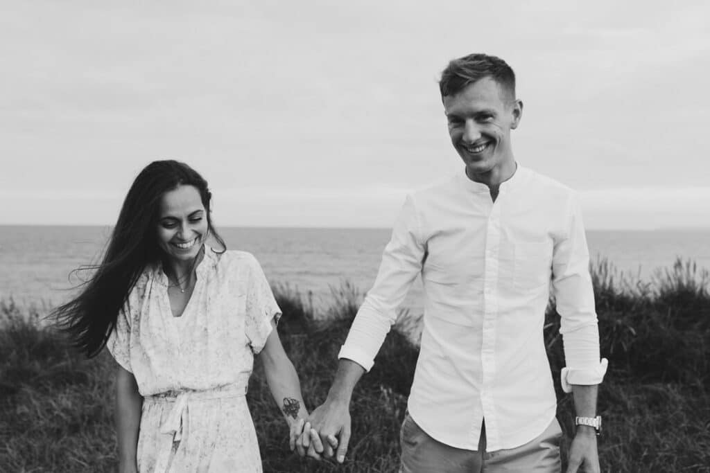 Couple is walking towards the photographer. They are both laughing and the man is looking at the camera. Lovely candid couple photography in Hampshire. Ewa Jones Photography