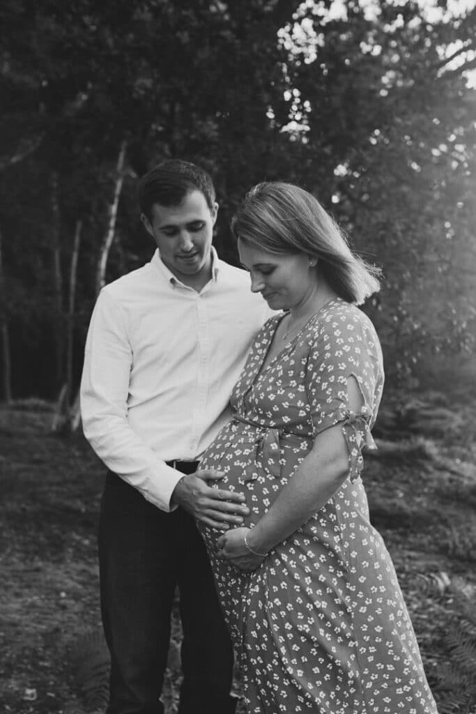 dad and expecting mum are both looking down at the baby. lovely black and white photograph of expecting parents. Maternity photographer in Hampshire. Ewa Jones Photography