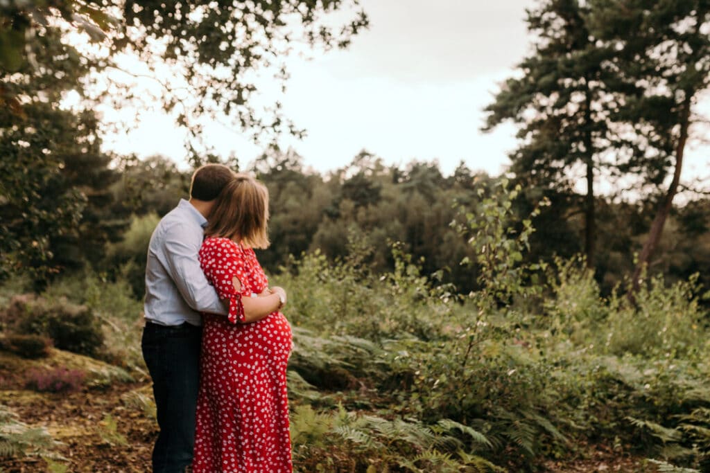 expecting mum and dad are cuddling to each other and looking away from the camera. maternity photoshoot in Hampshire. Ewa Jones Photography