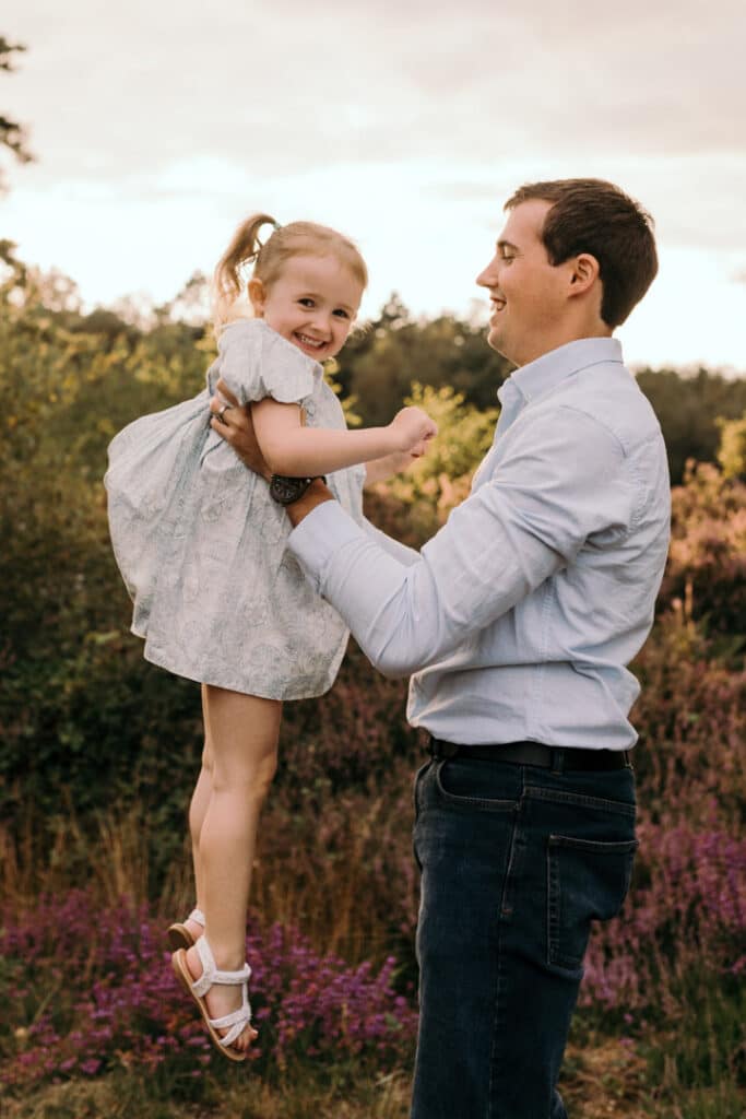 dad is lifting up his daughter in the air and they are both laughing. family photographer in Basingstoke, Hampshire. Ewa Jones Photography