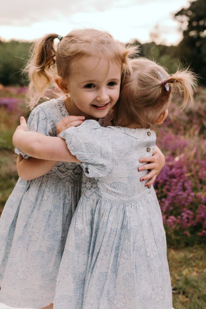 two lovely sisters and giving each other a cuddle. Lovely family photo session during sunset. Family photographer in Hampshire. Ewa Jones Photography