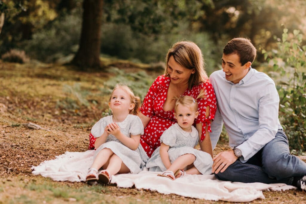 Family of four are sitting on the blanket. its a lovely summer evening and photo session is during golden hour. Family photographer in Basingstoke, Hampshire. Ewa Jones Photography