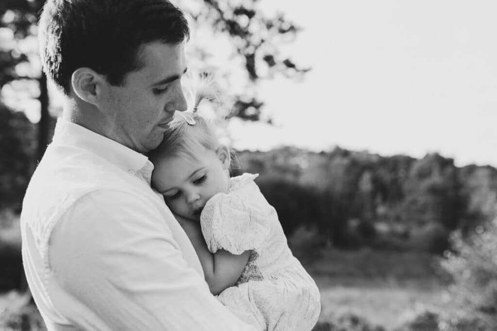 Little girl is cuddling up to her dad. Black and white photograph. family photographer in Basingstoke, Hampshire. Ewa Jones Photography