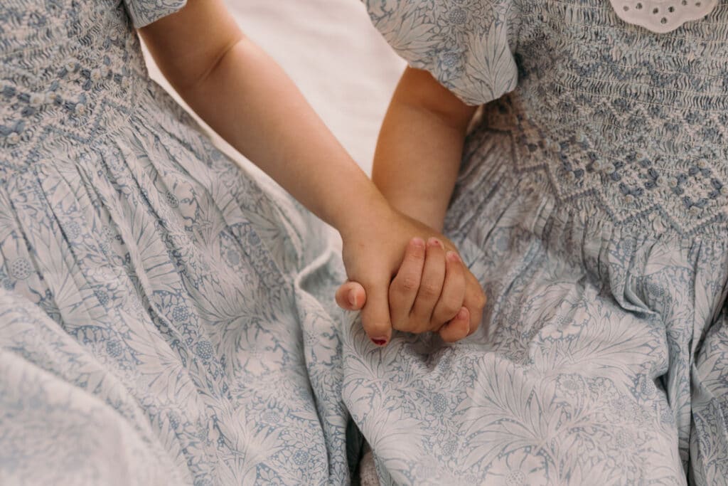 two little sisters are holding hands and wearing lovely blue and white dresses for a family photo session in Hampshire. Ewa Jones Photography