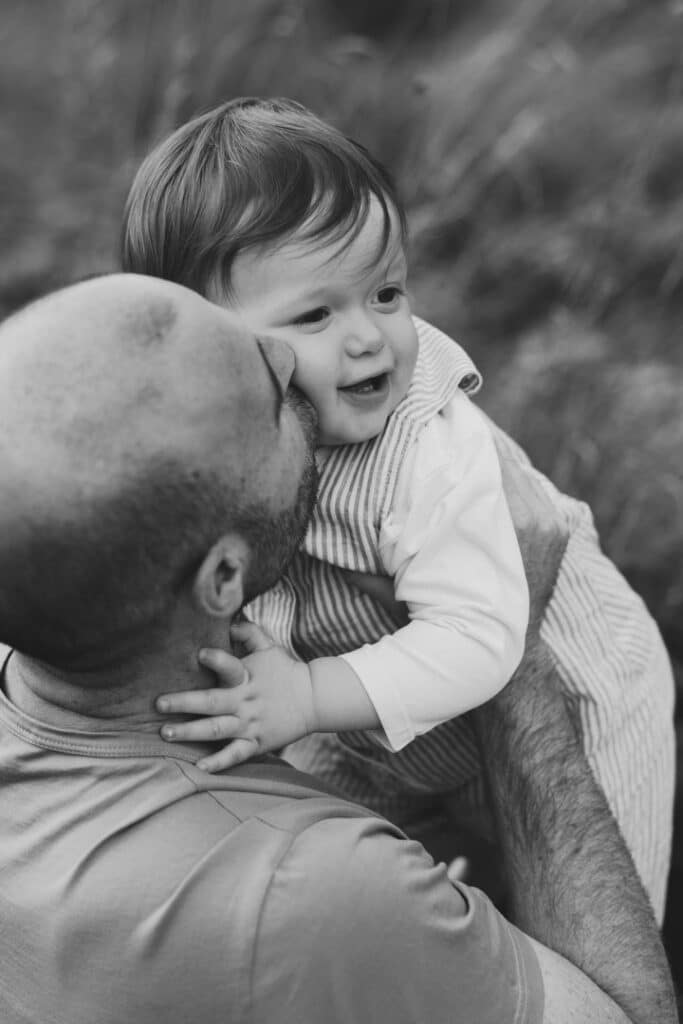 dad is kissing his boy on the cheek. Black and white photography. family photographer in Basingstoke, Hampshire. Ewa Jones Photography