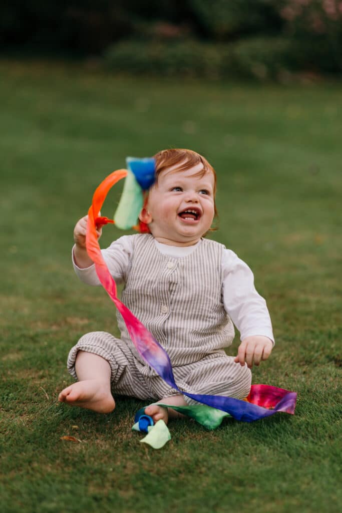 Little boy is holding a colorful ribbon and laughing. family photo session in Hampshire. Ewa Jones Photography