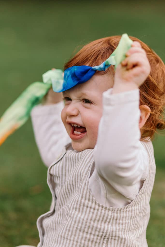 Little boy is holding a colorful ribbon and laughing. family photo session in Hampshire. Ewa Jones Photography