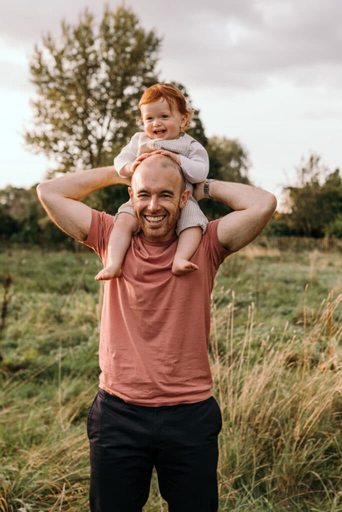 Dad is holding his boy on his shoulders and boy is laughing. family lifestyle photography in Hampshire. Ewa Jones Photography